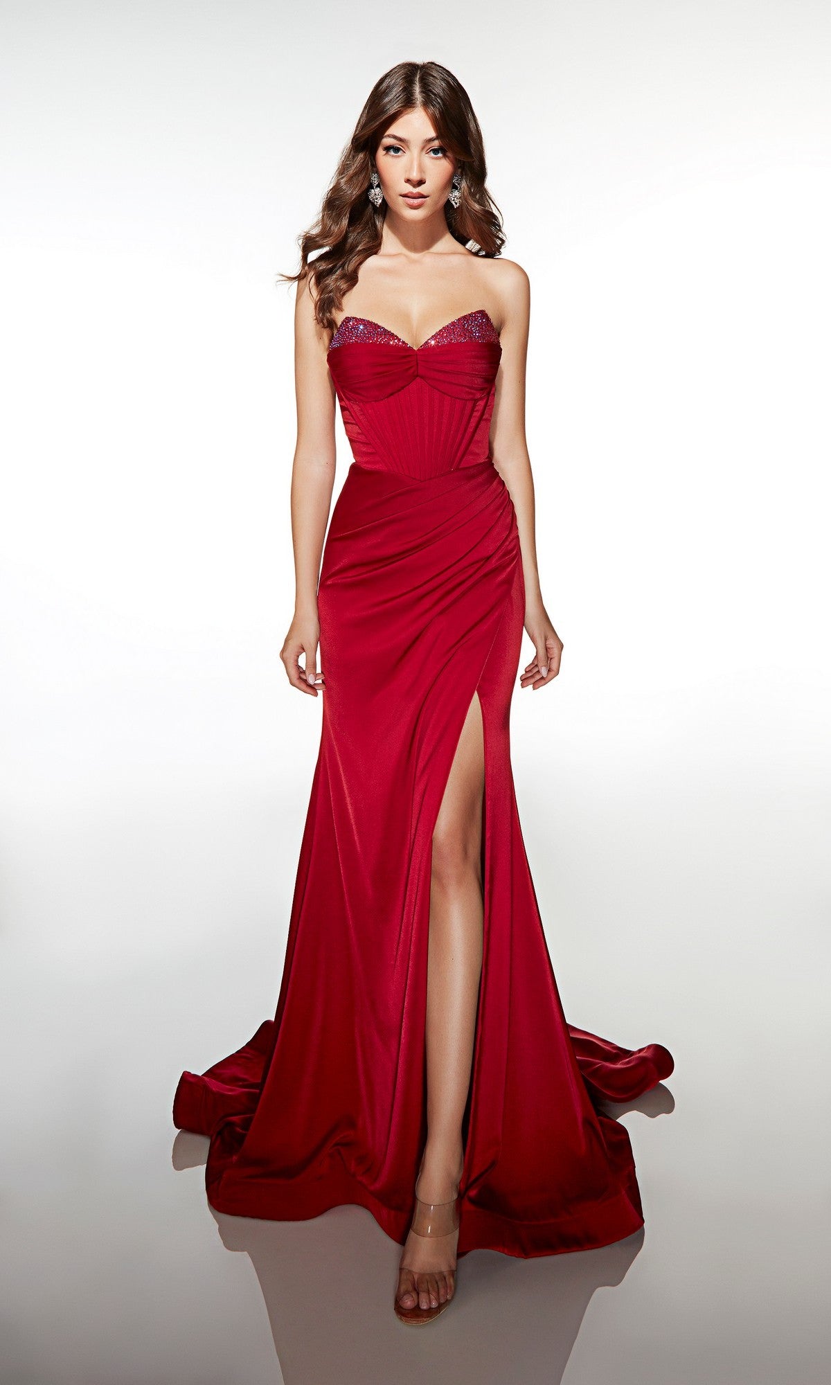 A woman stands against a plain white background wearing the Alyce 62062 long prom dress, featuring a strapless satin design with a sequin-embellished neckline and high slit.